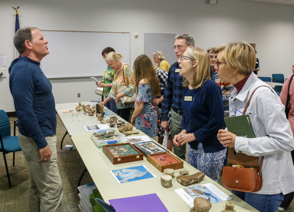 A group assembled around a table looking at marine fossils found in Texas.