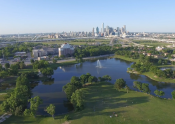Dallas skyline in the distance. Foreground grassy park land with a pond in the midground.