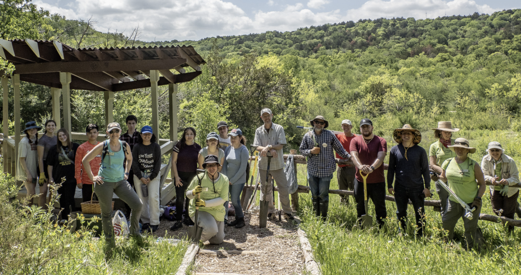 A group of Master Naturalists pose in front of a hilly natural area.